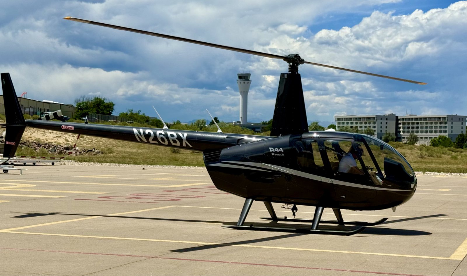 N26BX, AirCam Vertical's 2023 Robinson R44 Raven II, on the ramp at Centennial Airport with the control tower behind