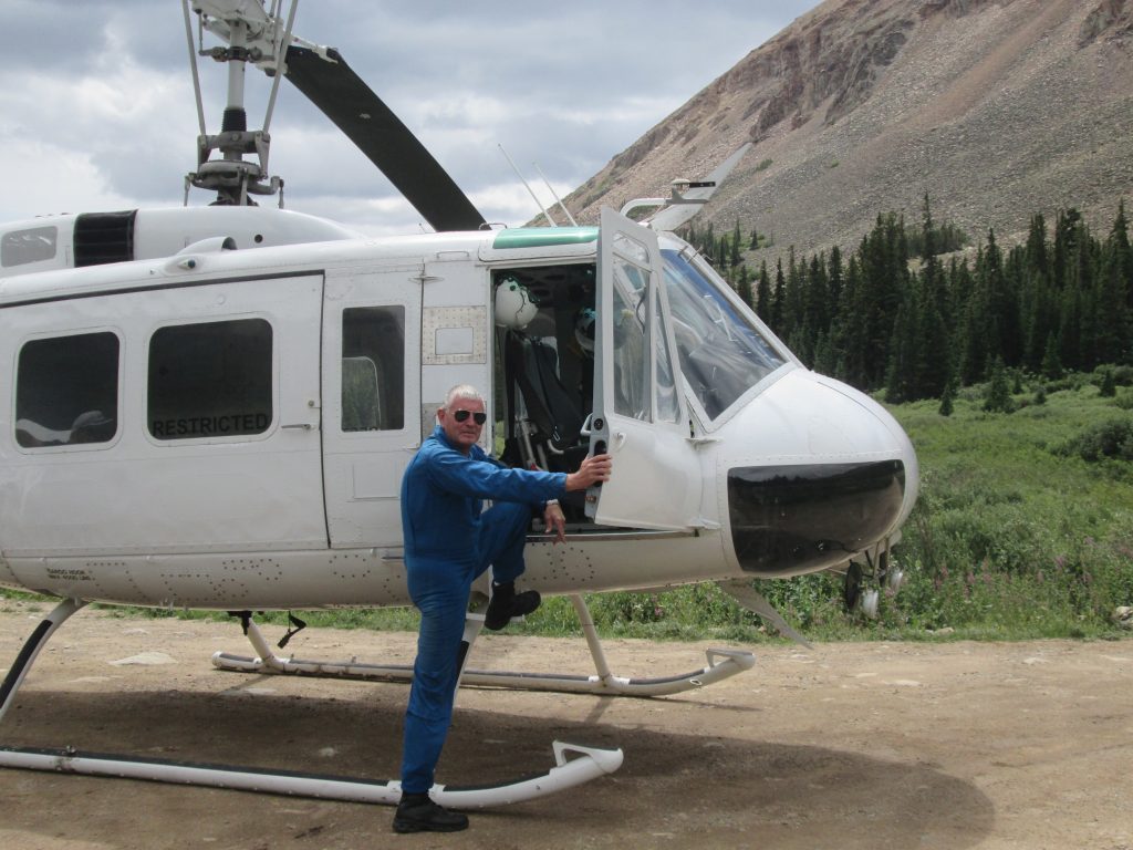 Pilot boarding a Bell 205 in a remote mountain valley